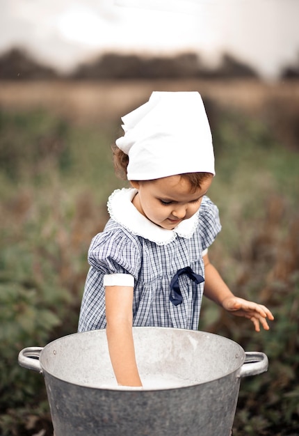 Baby girl washing dolls in a tin basin. Retro style. Countryside concept.