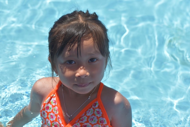 더운 여름날 수영장에서 비키니를 입은 아기 소녀는 수영을 배웁니다.