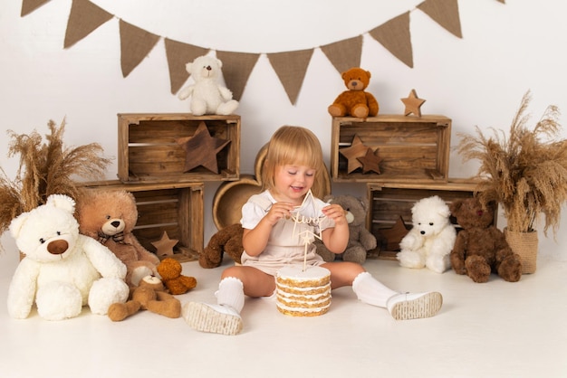 Baby girl on a white background with a cake and teddy bears.