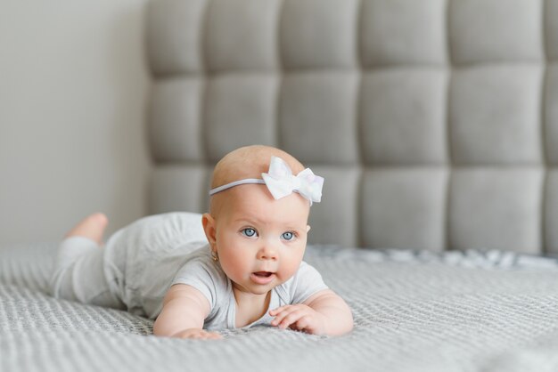 A Baby girl in white bedding at home look nice