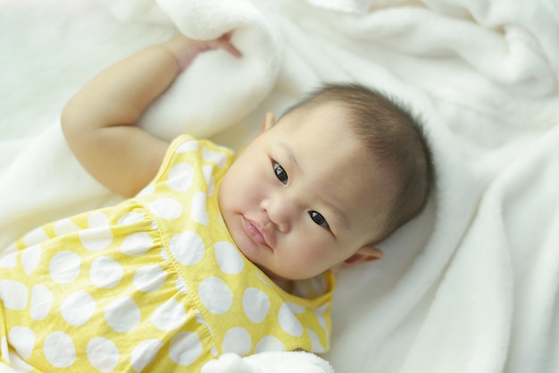 A Baby girl in white bedding at home.