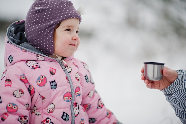 冬の日の女の赤ちゃんは熱いお茶を飲みます。
