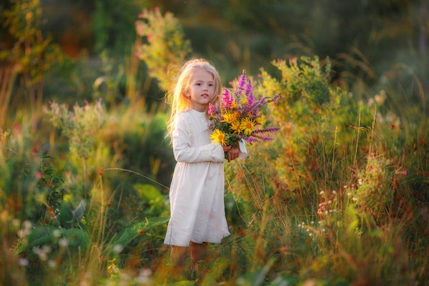 Baby girl with a bouquet of wild flowers