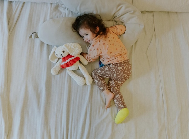 A baby girl with a cast on her leg lies on the bed