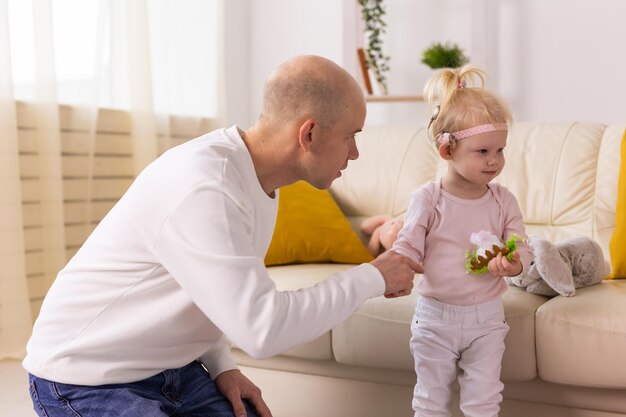 Baby girl with cochlear implants playing with her father at home Deafness and medical technology concept