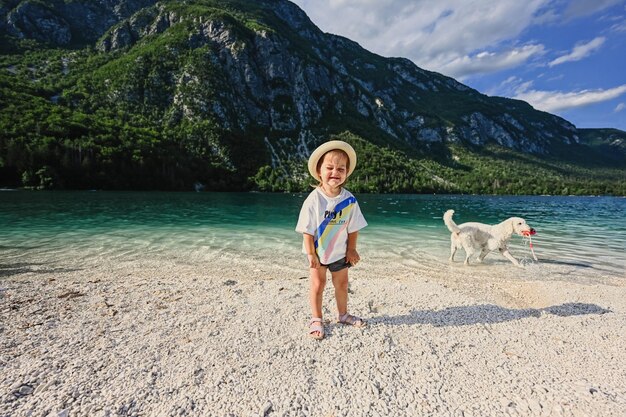 Baby girl with dog against lake bohinj the largest lake in slovenia part of triglav national park