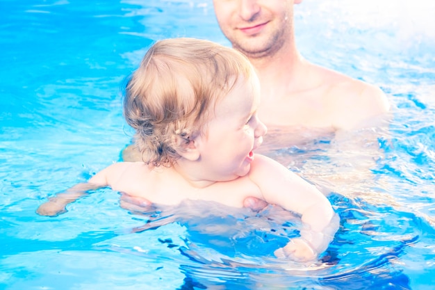 Bambina con il padre in una piscina il piccolo bambino impara a nuotare