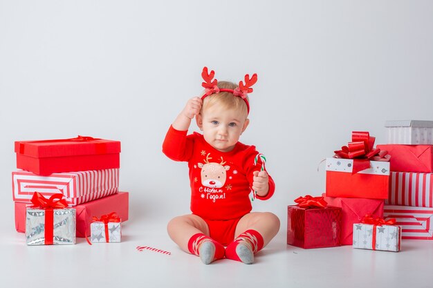 白い背景の上の贈り物を持つ女の赤ちゃんは、クリスマスの新年を分離しました