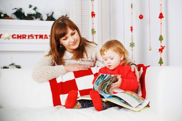 La neonata con la madre legge un libro all'interno con le decorazioni di capodanno