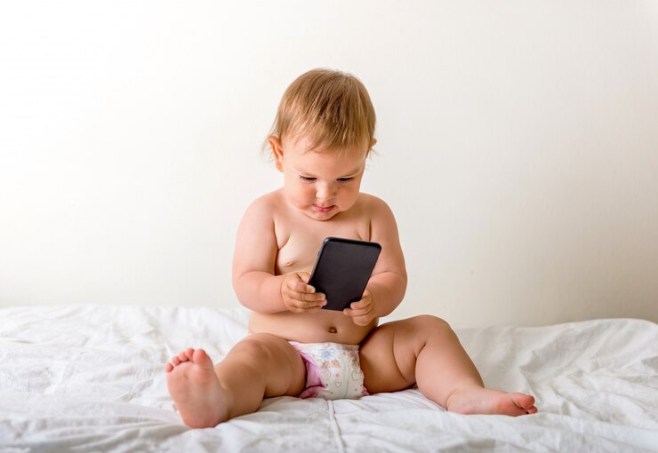 彼女の耳の近くに携帯電話で女の赤ちゃん