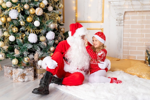 Baby girl with Santa Claus at the Christmas tree