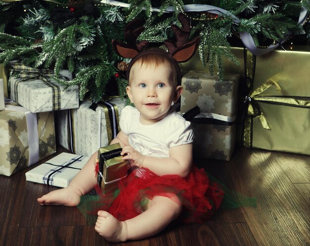 사진 크리스마스 트리를 장식하는 선물 상자 근처의 아기 소녀 행복한 시간