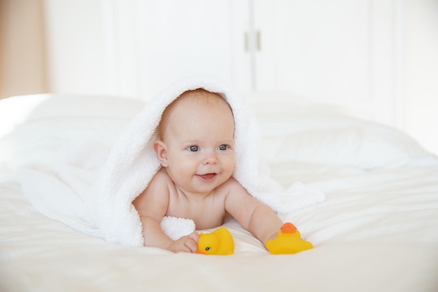 baby girl wrapped in a towel lying in the bedroom after bathing