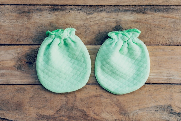 baby gloves on wooden background with space