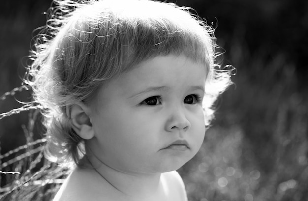 Baby in grass at sunny summer evening serious child outdoors baby face close up funny little child