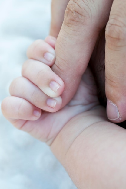 Baby hand grabbing the toe of his father