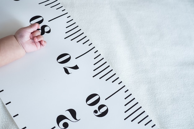 Photo baby hand and measuring tape: concept of baby growth, height, development