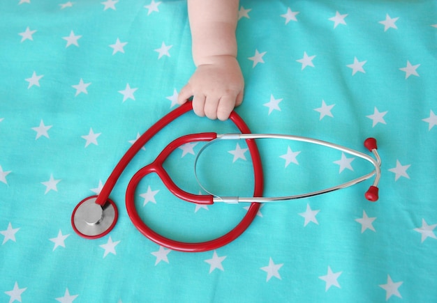 Photo baby hand and stethoscope on bedsheet baby health concept