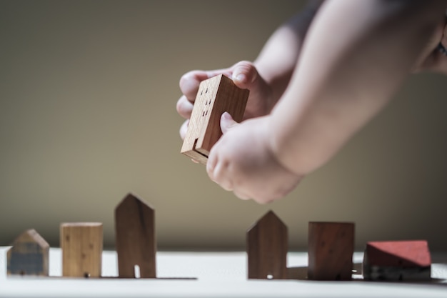 Baby Hands holding a house model. The concept of relocation, mortgage, inheritance, 