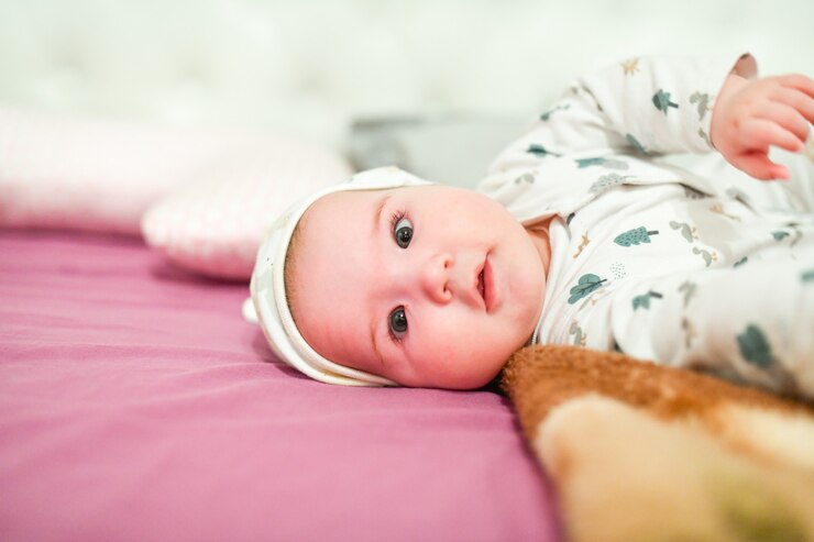 Baby in a hat at home. Cute baby in hat on the bed having fun .