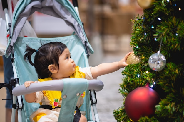 Baby het spelen met Kerstmisbal en pijnboomboom