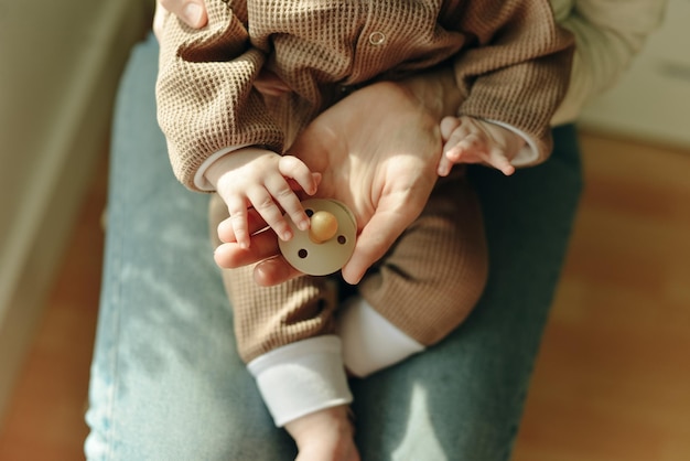 Baby houdt een fopspeen in de armen van zijn moeder