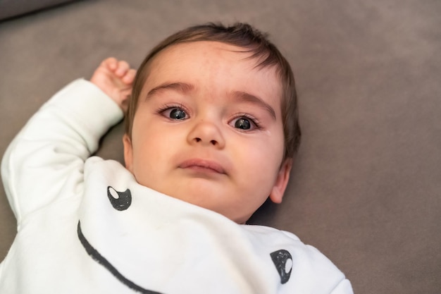 Baby huilend van de pijn van zijn eerste tandjes, liggend op de bank thuis