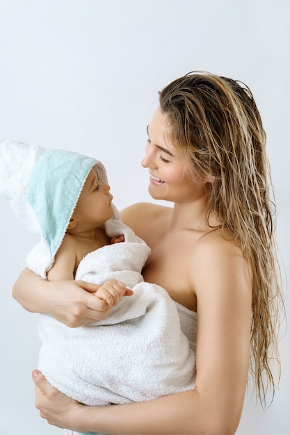 Гигиена и уход за младенцами. Молодая и счастливая мать и ее милый младенческий сын после купания.