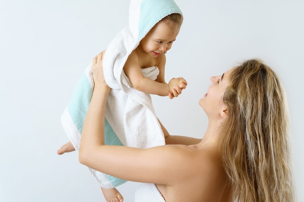 Baby hygiene and care. Young and happy mother and her cute infant son after bathing.