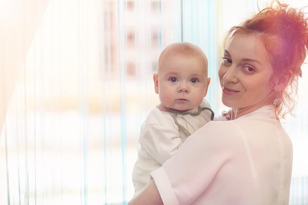 Baby in de armen van het meisje. Moeder houdt haar kind in haar armen. Gelukkige moeder met een kleine baby