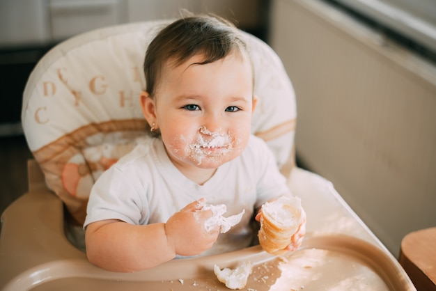 Baby in de keuken gretig eet de heerlijke slagroomhoorns, gevuld met een vanille crème erg grappig