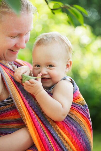 Baby in draagdoek buiten. Moeder draagt haar kind en toont natuurdetails