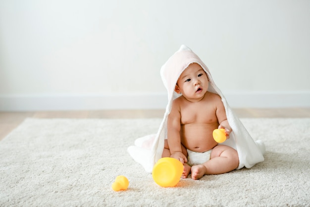 Baby in een badhanddoek met badeendjes