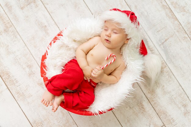 Baby in een kerstman kostuum slapen op een lichte houten achtergrond