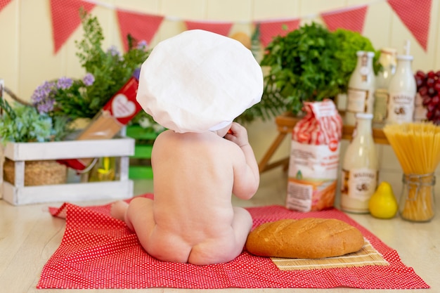 Baby in een koksmuts met eten om hem heen