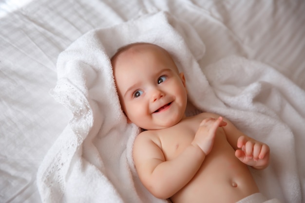 Baby in een luier ligt in de slaapkamer op het bed glimlachend