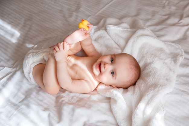 Baby in een luier ligt in de slaapkamer op het bed glimlachend