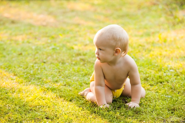 Baby in een luier zittend op groen gras op zomerdag