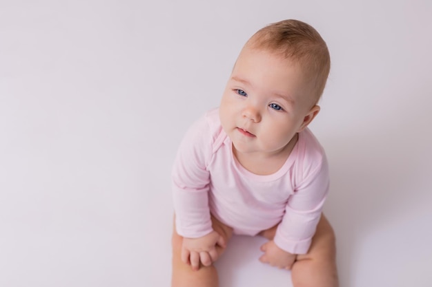 Baby in een roze bodysuit zit op de vloer bovenaanzicht ruimte voor tekst hoge kwaliteit foto