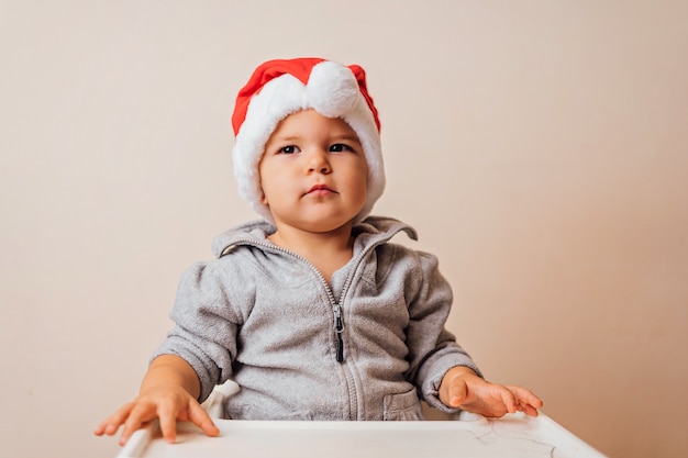 Baby in kerstmisbonnet die omhoog de pop, op witte achtergrond kleedt. kopie ruimte