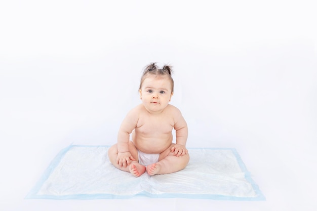 Baby in luiers zittend op een wegwerpluier op een witte geïsoleerde achtergrondruimte voor tekst babyhygiëne