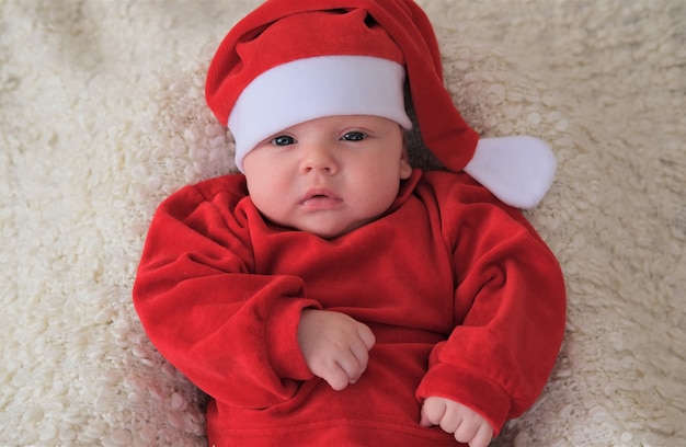 Baby in santa kostuum op wit. Kerst peuter in kerstmuts.