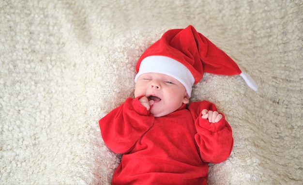 baby in santa kostuum op witte achtergrond. Kerst peuter in kerstmuts