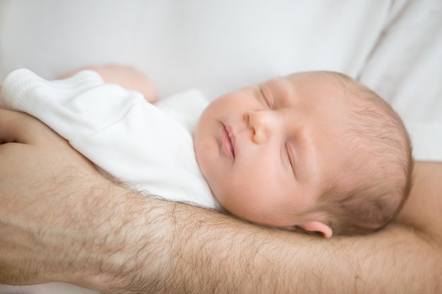 Baby in slaap in de armen van zijn vader