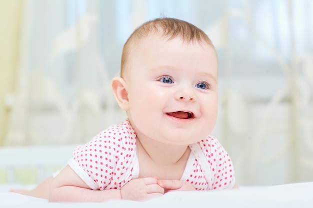 Baby,infant smiling while lying on a white bed.