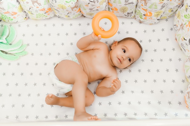 Малышке 11 месяцев. милый ребенок в подгузнике лежит и улыбается.
