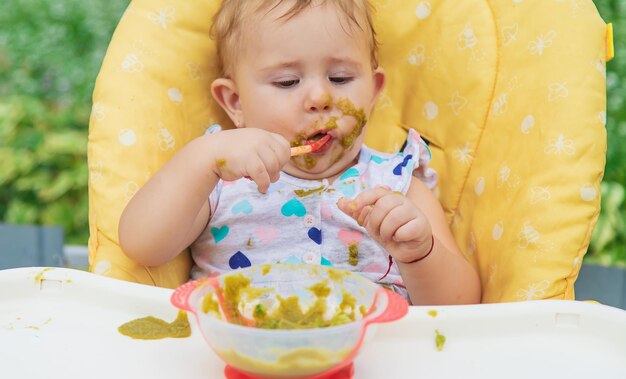 Ребенок ест овощное пюре. Выборочный фокус. Ребенок.