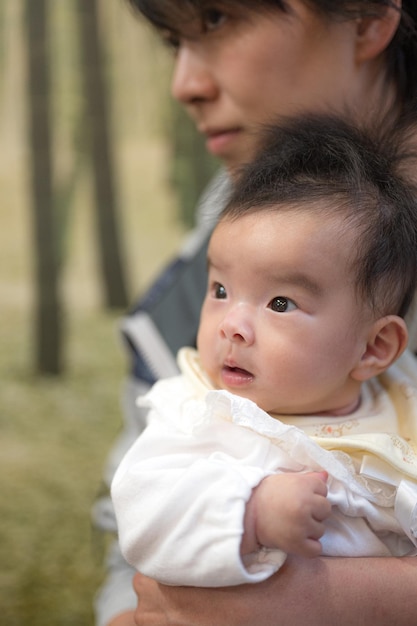 아기는 어머니를 안고 있는 여성에게 안겨 있습니다.