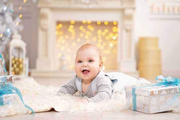 The baby is lying on a fluffy carpet with gift boxes