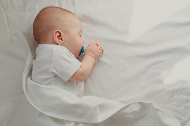 The baby is lying in his crib and looking at the camera A happy child Children's article